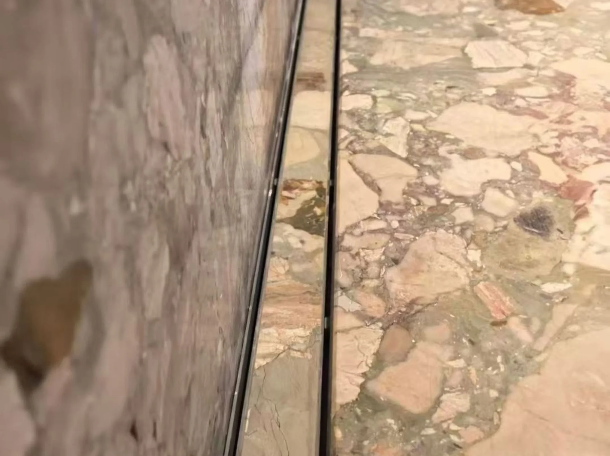 ceppo-siciliano-marble-floor-wall-edge-detail-01.webp ceppo siciliano marble floor wall edge detail with soft beige green breccia texture
