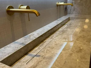 Custom Brazilian Taj Mahal Quartzite double trough washbasin with wall-mounted brass faucets