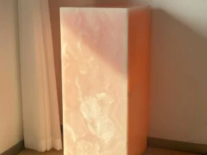 Backlit Iris Pink Onyx feature column glowing with warm coral and white translucent patterns