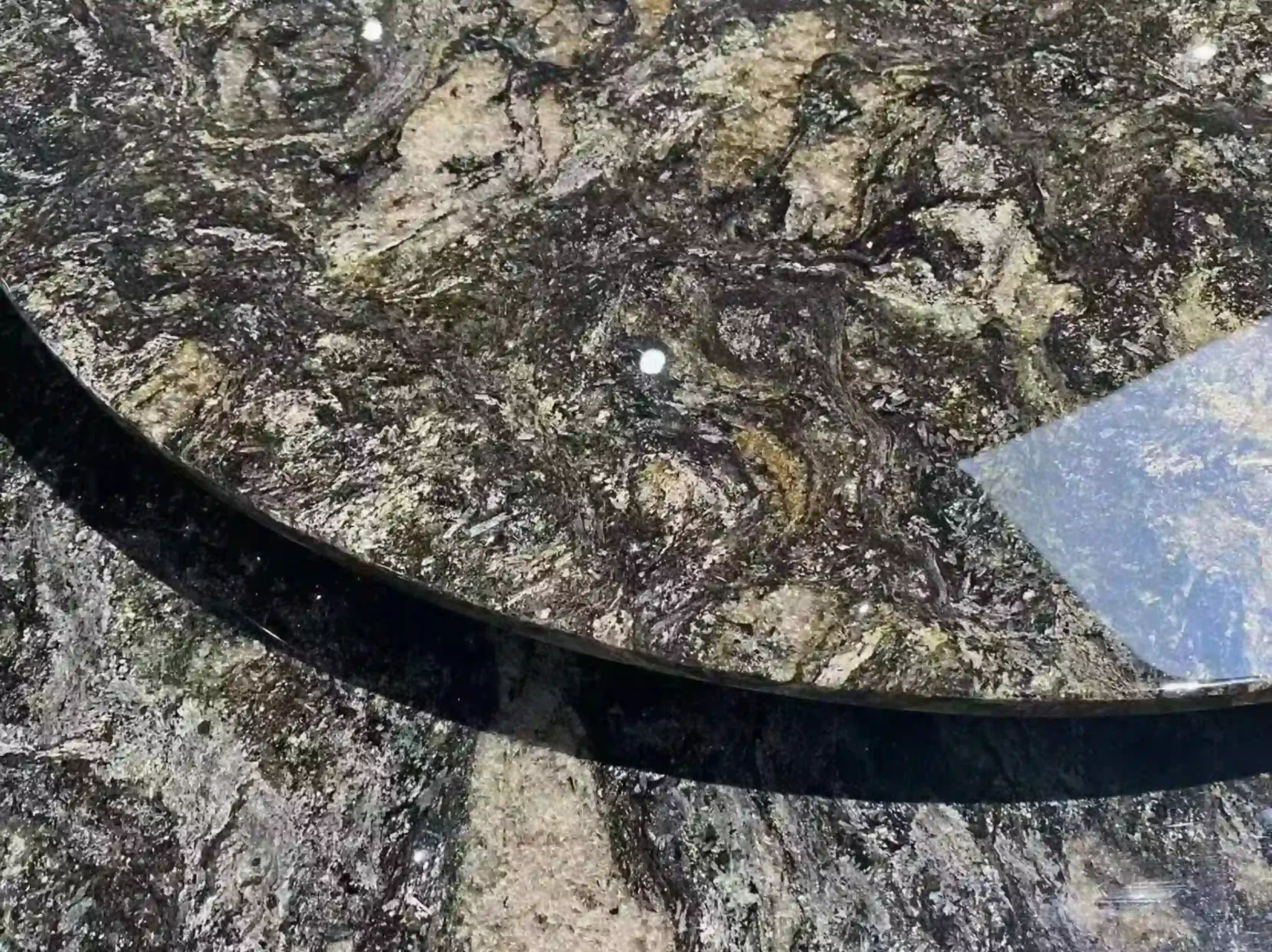 kozmus-black-granite-round-table-detail-01.webp kozmus black granite round table top with dark grey green and warm mineral movement