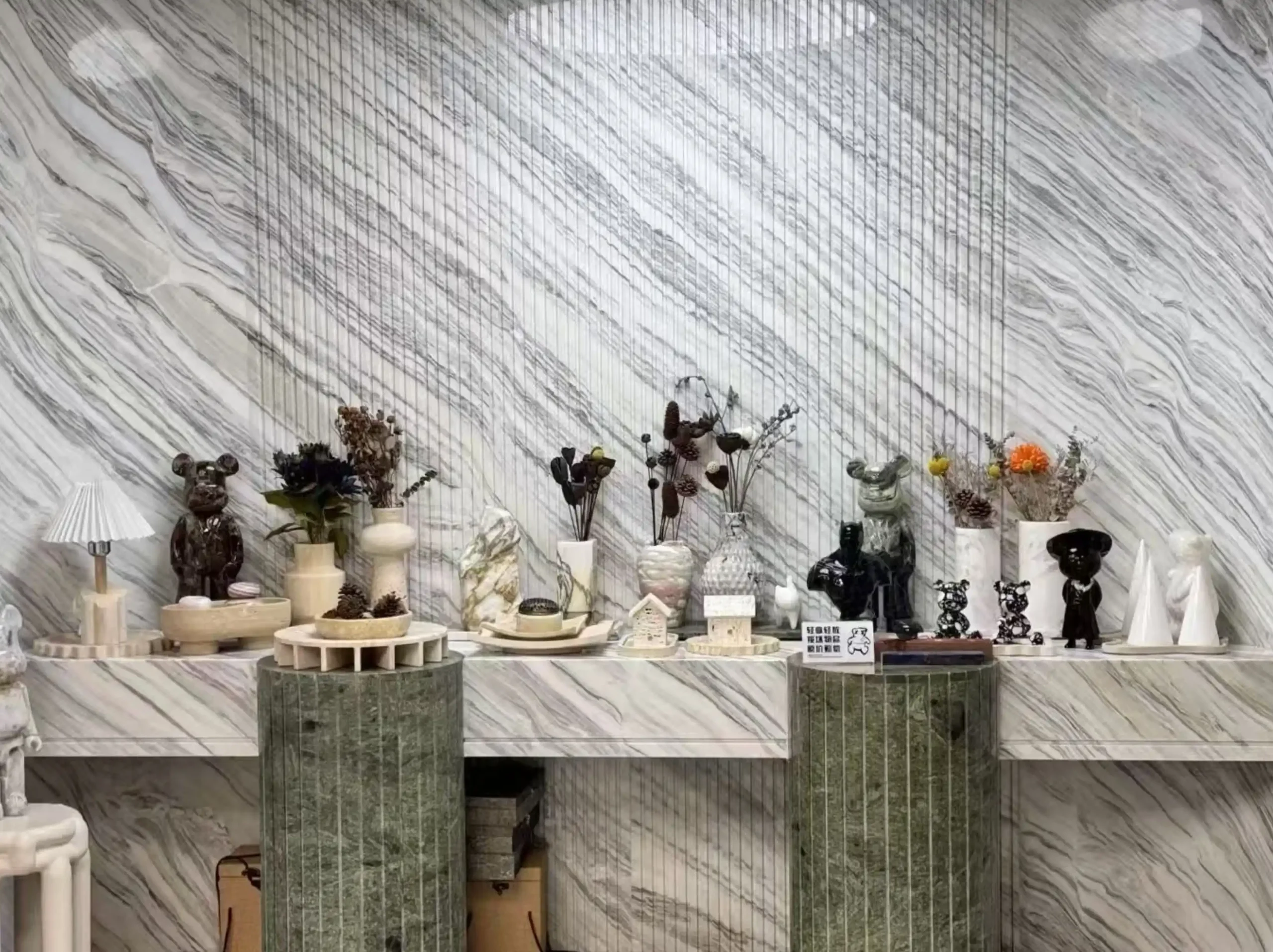 marmi-bianco-ondulare-marble-showroom-wall-display.webp Marmi Bianco Ondulare Marble showroom feature wall with green display counter