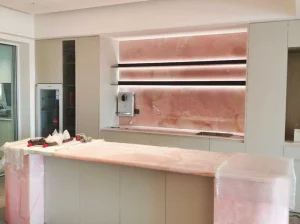 Backlit Onice Rosso kitchen backsplash and custom island with translucent rose-pink stone panels