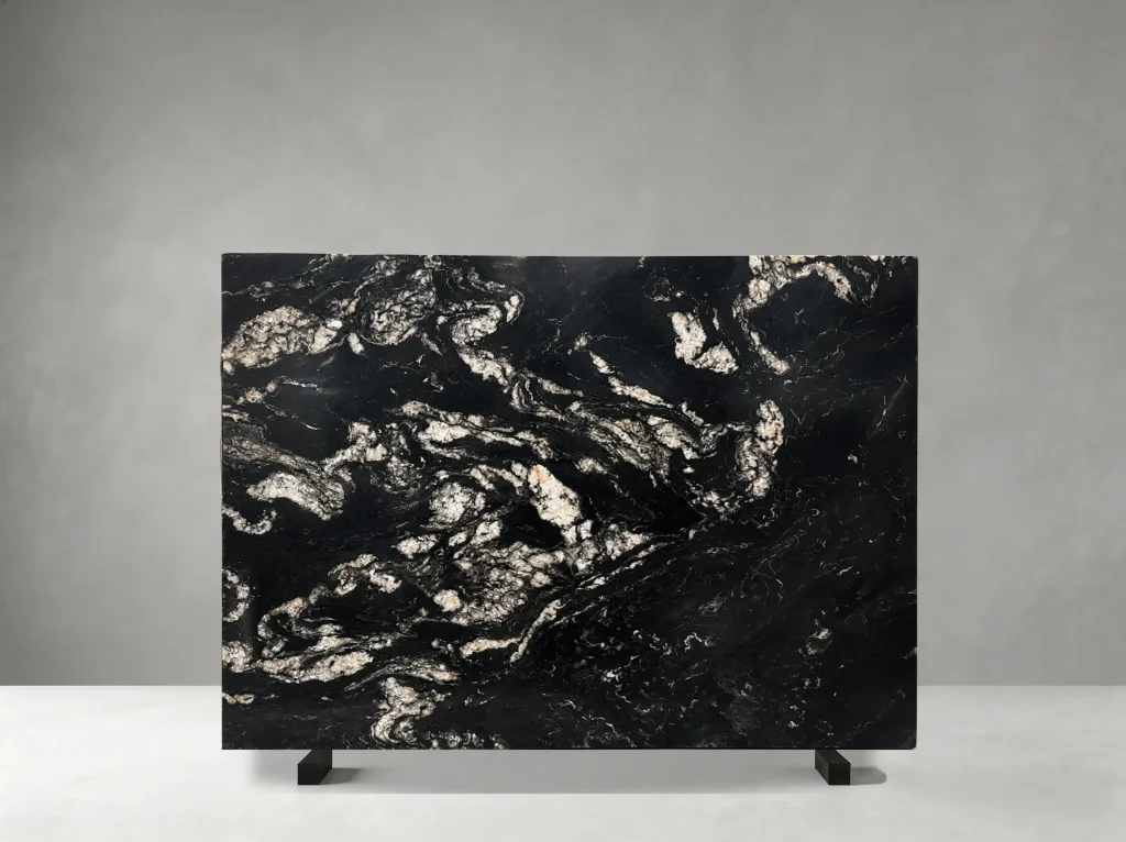 Brazil Titanium Granite full slab showing black, charcoal, silver-white and warm gold tones with large flowing mineral patches and dramatic wave-like crystalline movement
