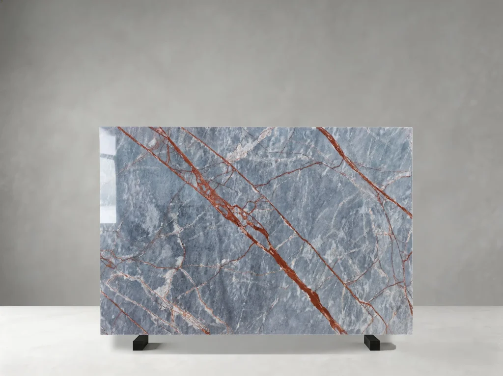 Deep River Marble full slab showing cool blue-grey, silver and pale grey tones with rust-red and copper linear veins crossing layered cloudy mineral movement